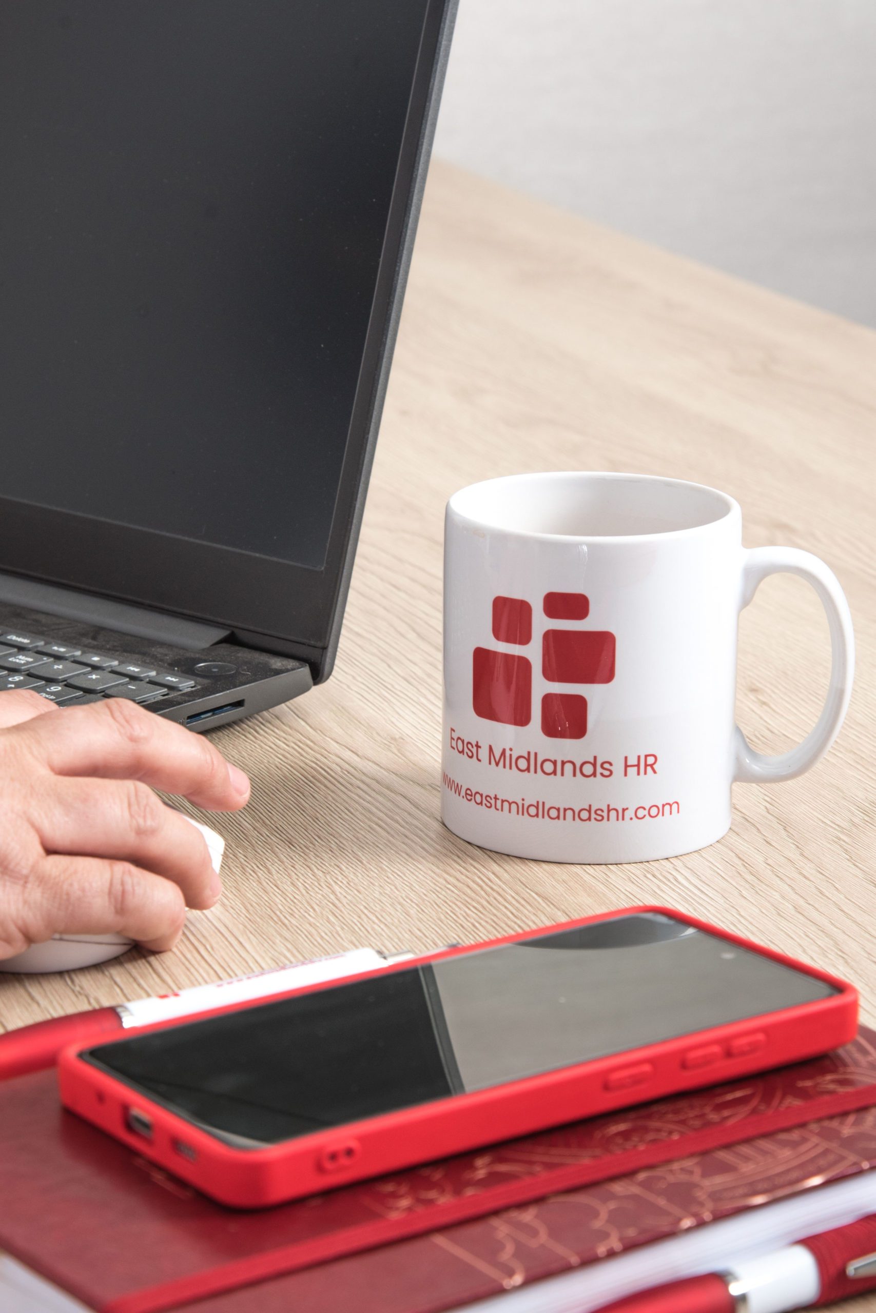 hand on a mouse to use a laptop for HR System Software